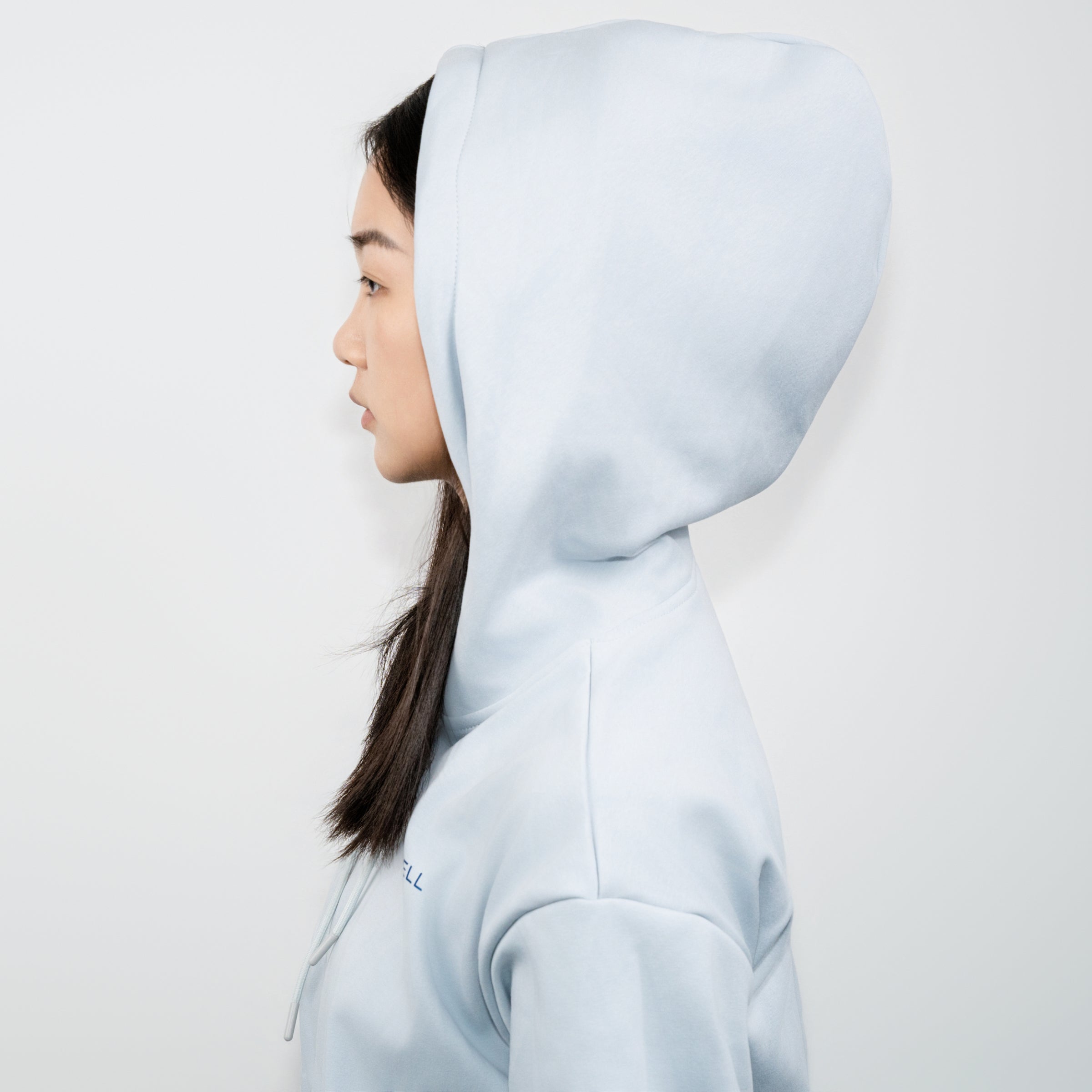 Side profile of a person wearing a light blue ZenoWell hoodie